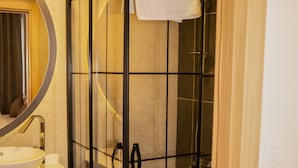 A modern bathroom with a glass-enclosed shower, a white sink, and a mirror with a wooden frame. - Mahall Hotel (Istanbul)