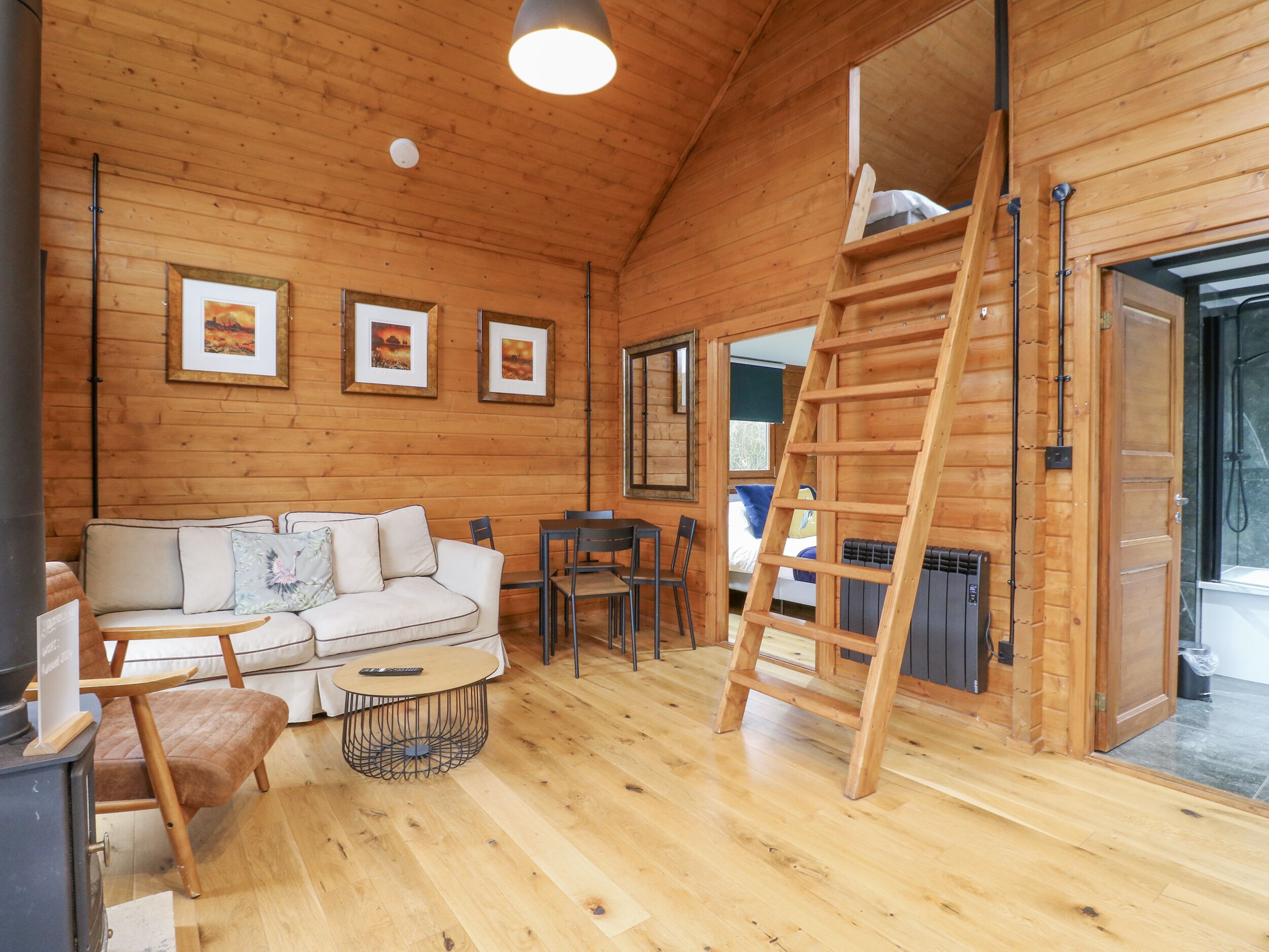 A cozy cabin interior with a wooden interior, a sofa, a table, and a ladder.