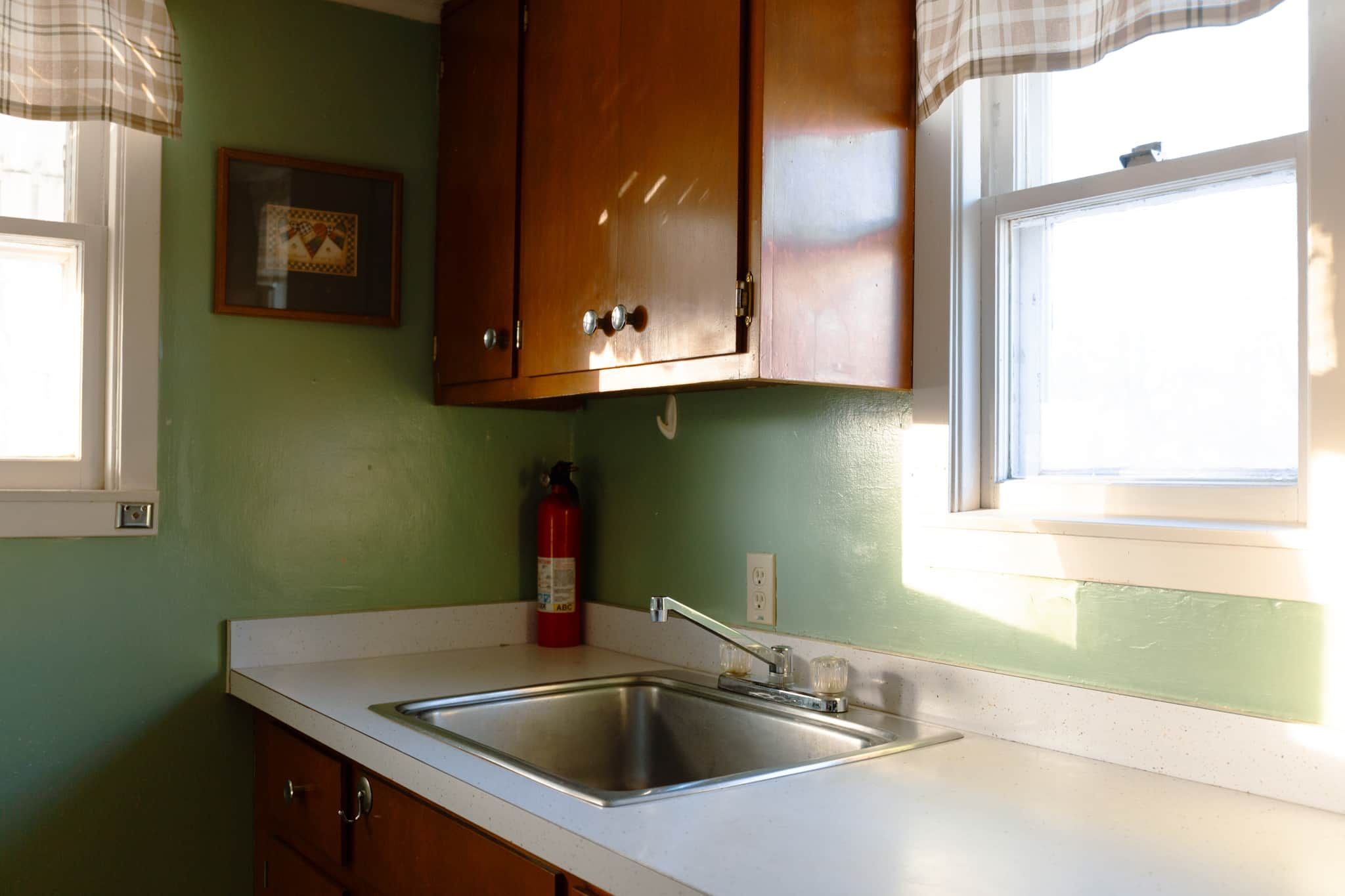 A kitchen with wooden cabinets, a stainless steel sink, and a fire extinguisher.
