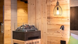 Een houten interieur met een glazen open haard, een hanglamp en een gestreept kussen.