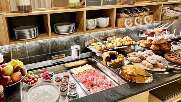 Een buffet met diverse gerechten, zoals gebak, fruit en vlees.