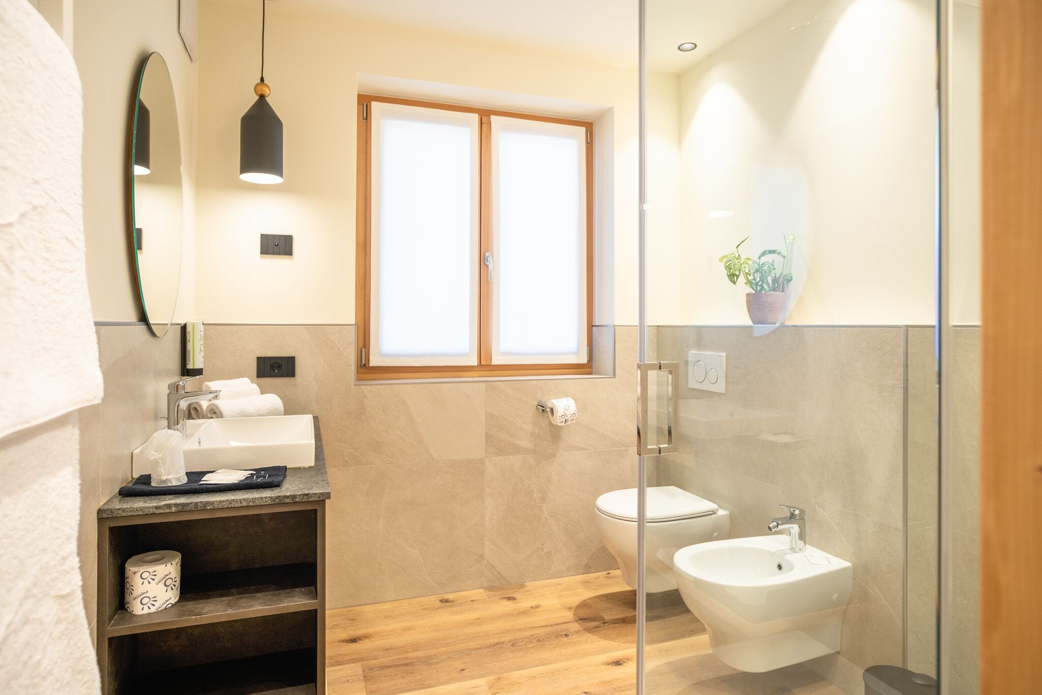 Un bagno moderno con box doccia in vetro, lavandino con specchio e water.