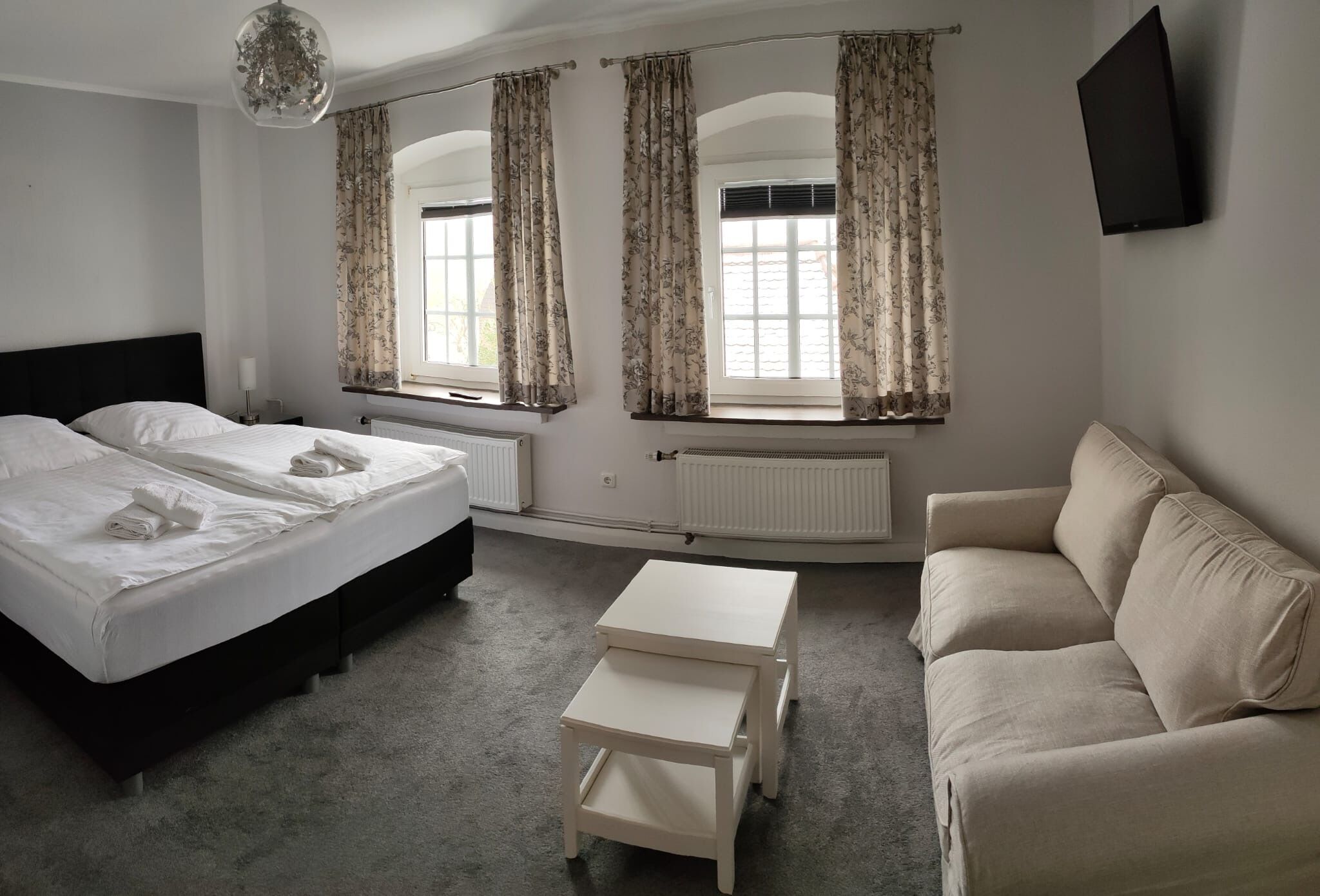 A bedroom with a bed, two bedside tables, a sofa, and a TV.