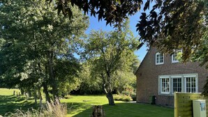 A brick house with a well-maintained lawn and trees. - Pension Nordwind (Hedwigenkoog)