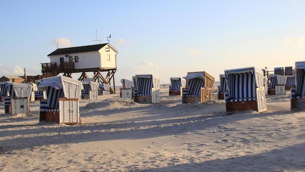 A beach with several beach chairs and a lifeguard tower. - Pension Nordwind (Hedwigenkoog)
