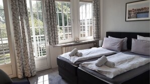 A bedroom with two beds, a radiator, and a window with curtains. - Pension Nordwind (Hedwigenkoog)