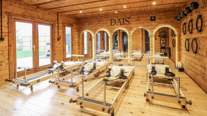 A wooden room with multiple massage tables arranged in rows, a visible door leading outside, and the word "DAIS" on the wall. - Otter's View (Oakham)