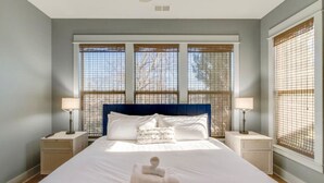 A bedroom with a large bed, two bedside tables, and a window with blinds. - Cleveland Park Charmer | Large Private Backyard (Nashville)
