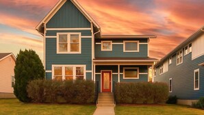 A two-story house with a red front door, a small porch, and a garage. - Cleveland Park Charmer | Large Private Backyard (Nashville)