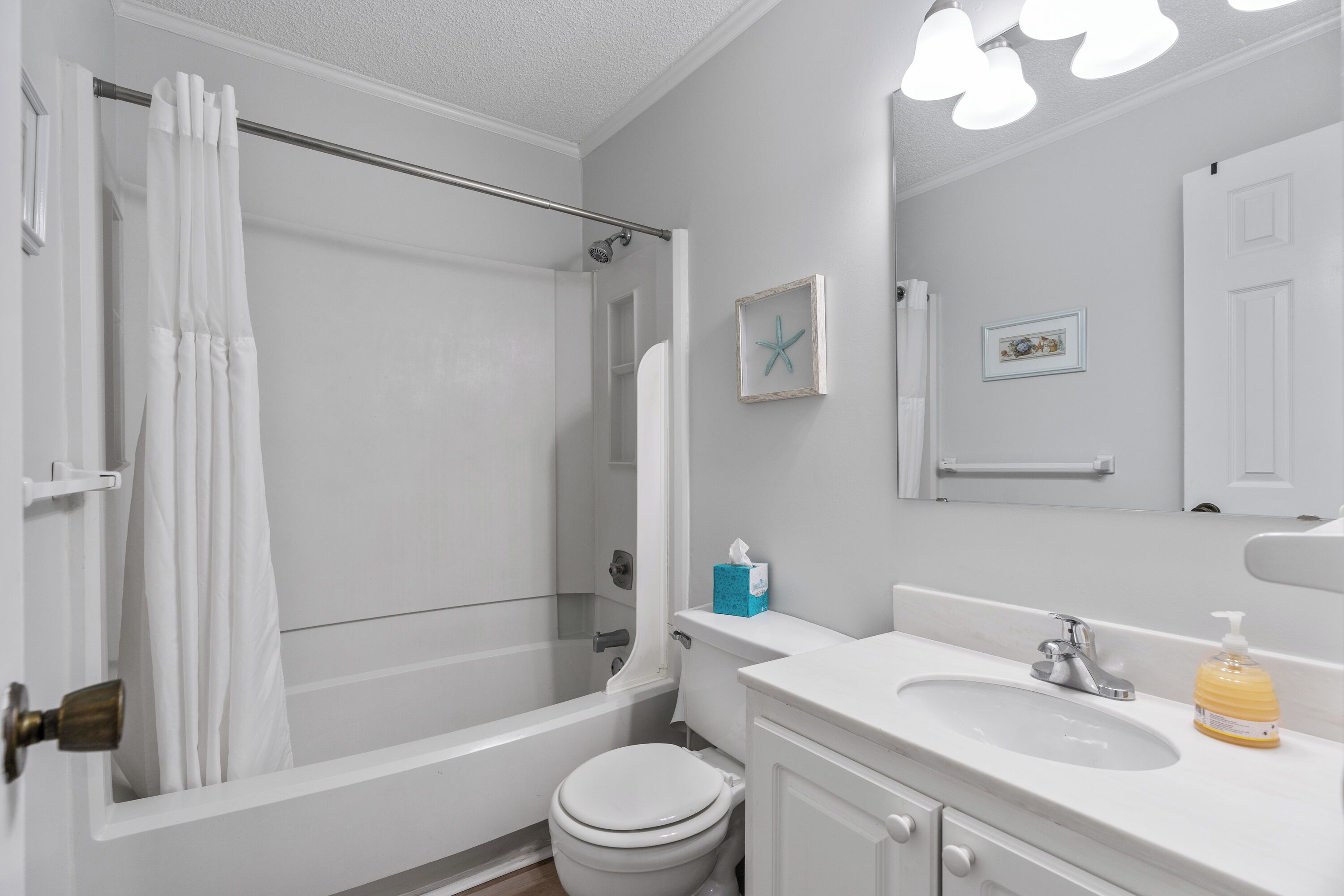 A bathroom with a bathtub, toilet, sink, and a mirror.