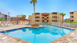A swimming pool with lounge chairs and a palm tree, surrounded by multi-story buildings. - Waipani D13 - Beach is Just Across the Street (North Myrtle Beach)