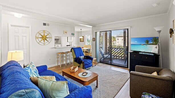 A living room with a sofa, armchair, and coffee table. There is a television and a window with a view of the outdoors. - Waipani D13 - Beach is Just Across the Street (North Myrtle Beach)