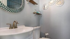 A bathroom with a white sink, a toilet, and a mirror with a decorative frame. - The Mermaids Lair 🧜‍♀️ (Portsmouth)