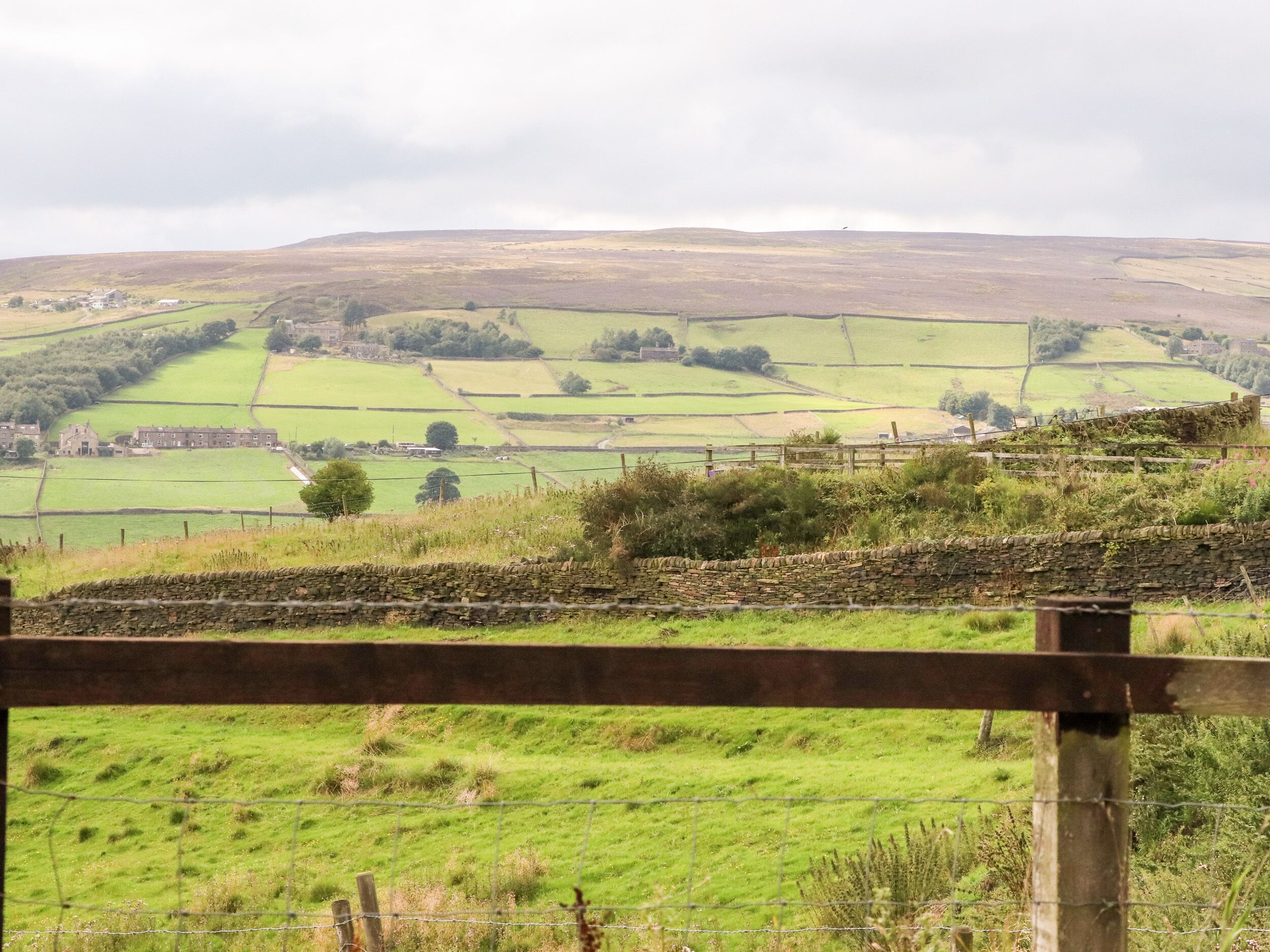 A rural landscape with fields, stone walls, and a distant building.