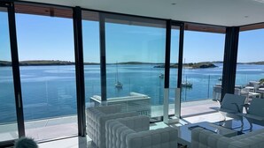 A modern living room with large windows overlooking a body of water and boats.