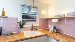 A kitchen with a wooden countertop, a sink, a window with blinds, and a shelf with plates and a roll of paper towels. - Family & Dog Friendly Fun New Renovation w/ Pool!
 (Savannah)