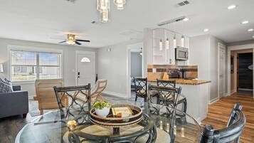 A modern kitchen with white cabinets, a microwave, and a wooden countertop.