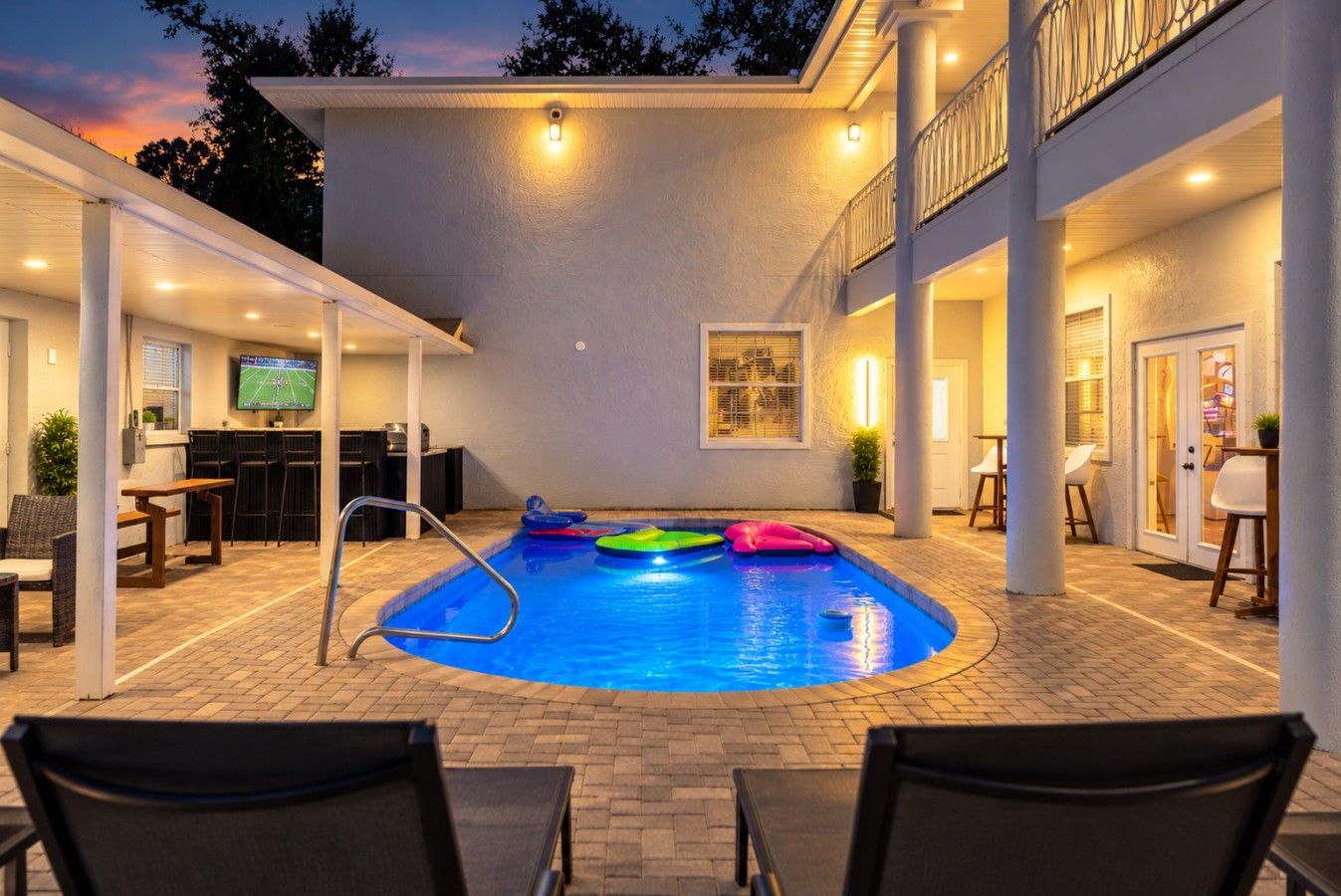 An indoor swimming pool with a pool ladder, surrounded by lounge chairs and a bar area.