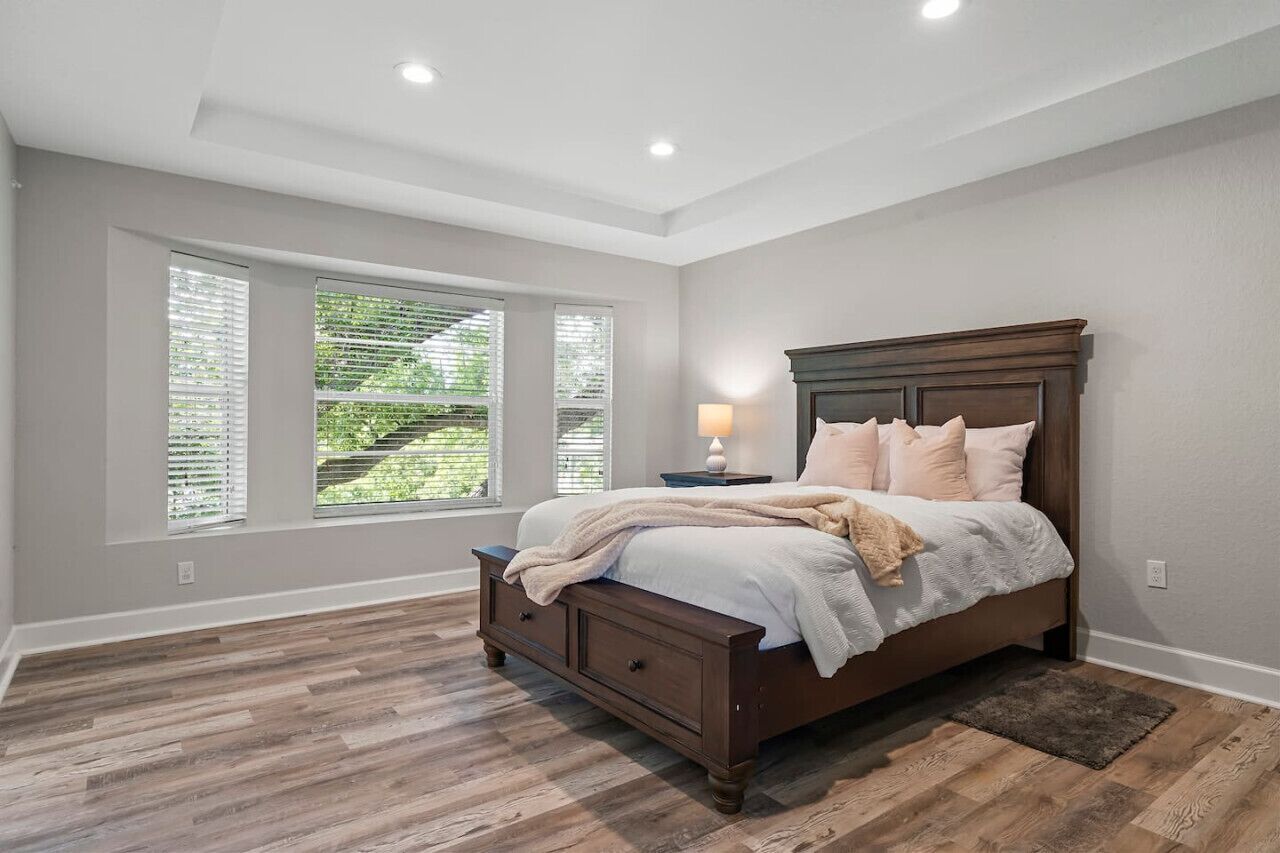 Un dormitorio con una cama grande, una mesita de noche y una ventana con persianas.