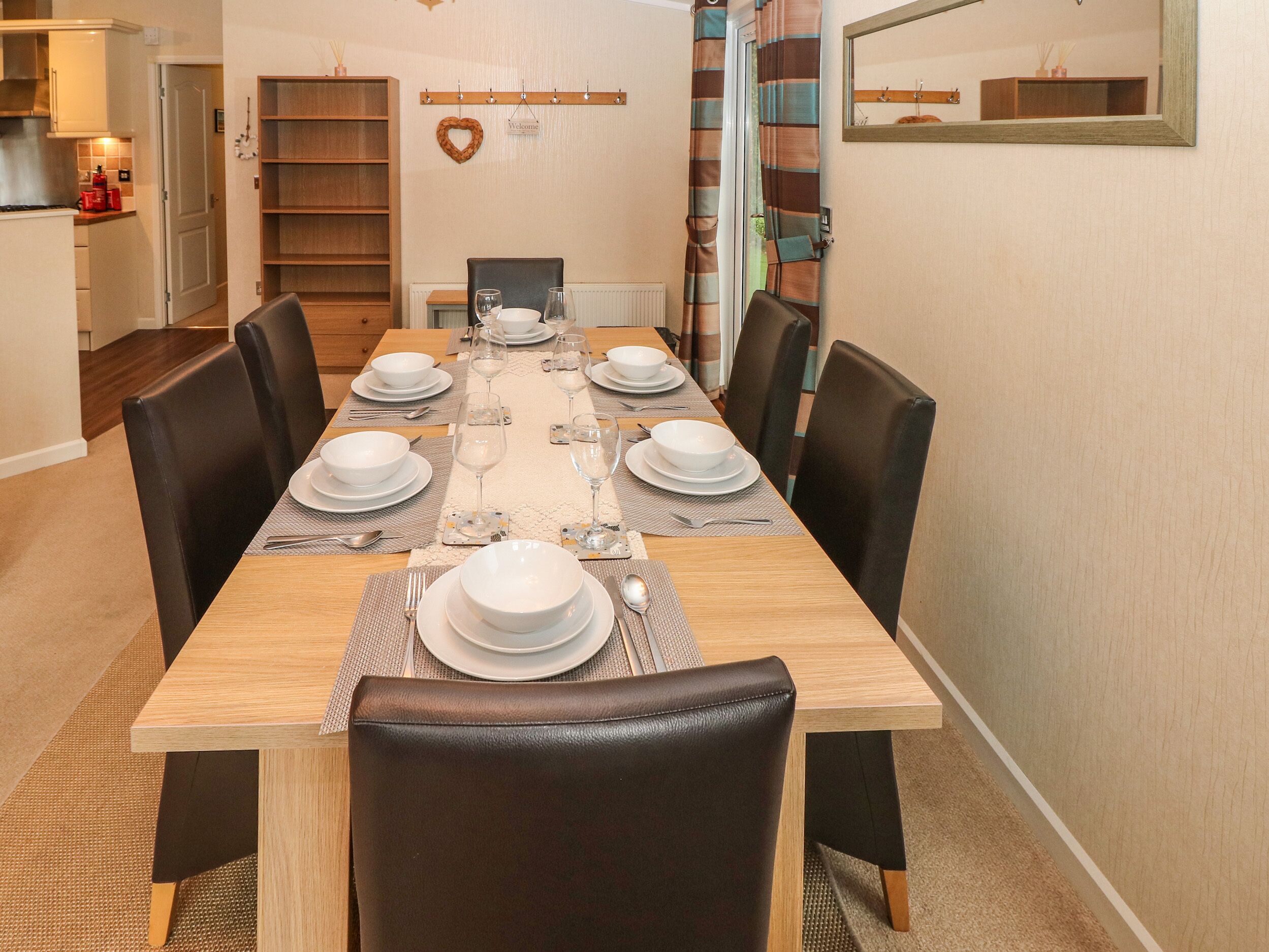 A dining area with a long wooden table set for six, surrounded by six chairs.