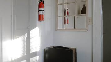 A room with a door, a fire extinguisher, a mirror, and a small table.