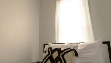 A bedroom with a bed, a ceiling fan, and a window with curtains.