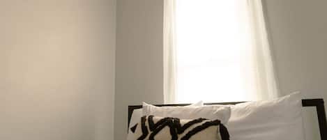A bedroom with a bed, a ceiling fan, and a window with curtains.