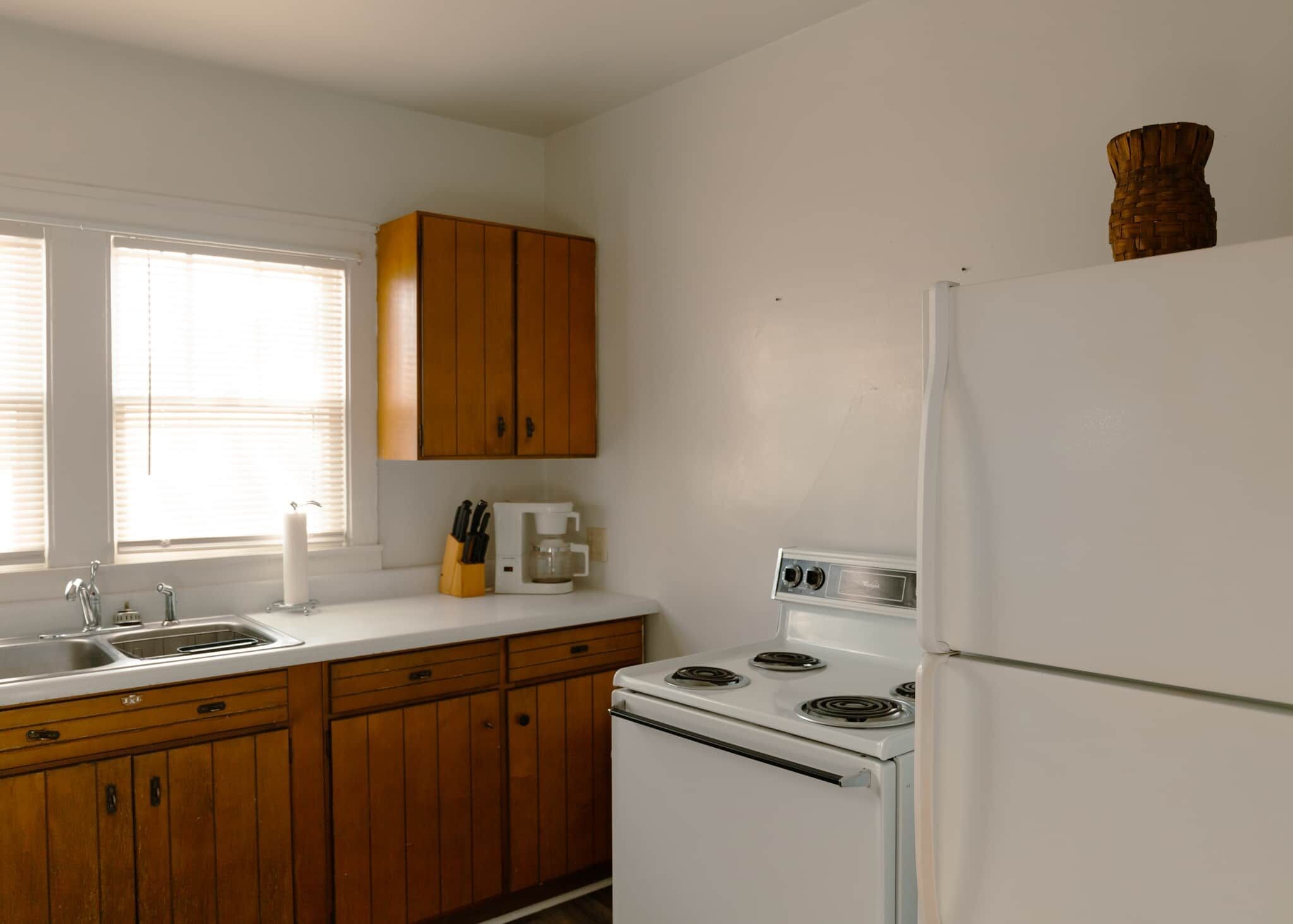 A kitchen with wooden cabinets, a white stove, and a refrigerator.