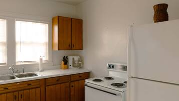 A kitchen with wooden cabinets, a white stove, and a refrigerator.