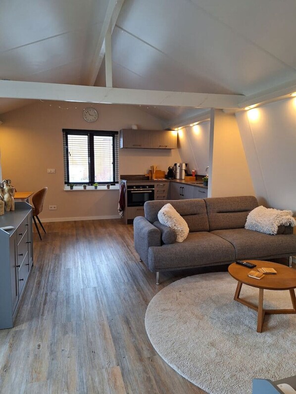 A compact living space with a kitchenette, a sofa, a dining area, and a small round table.