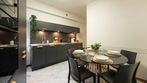 Una cucina moderna con mobili scuri, un tavolo da pranzo in vetro e una pianta sospesa.