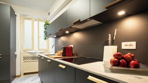 Una cucina moderna con mobili scuri, piano cottura integrato e un ripiano con delle mele.