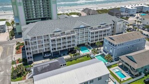 A hotel with multiple floors, a swimming pool, and a view of the beach.