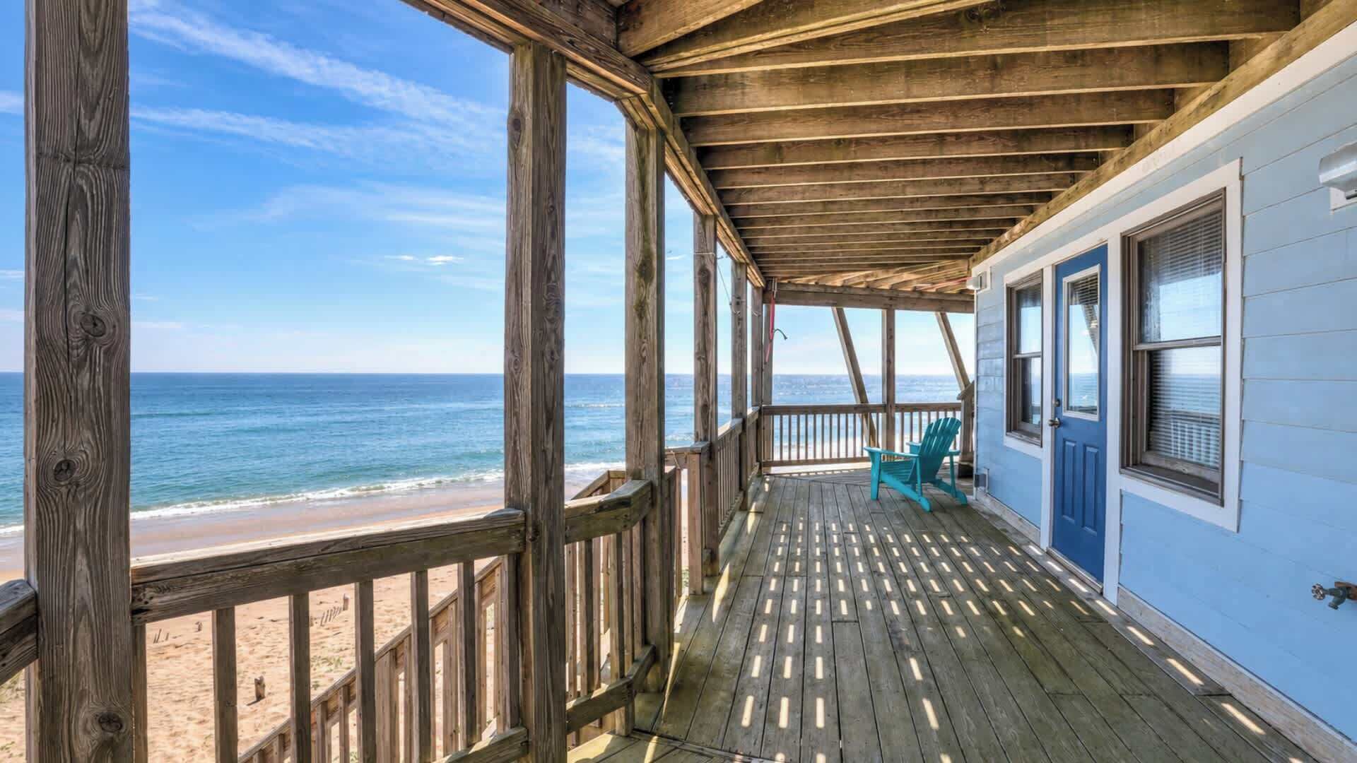 A wooden deck with a view of the ocean, a door, and a window.