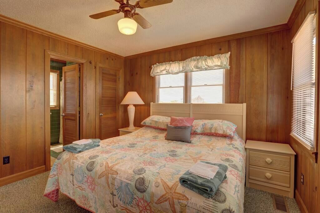 A bedroom with a bed, a nightstand, a lamp, and a ceiling fan.