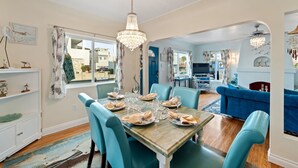 A dining area with a table set for four, blue chairs, and a chandelier.