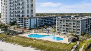 A hotel with a swimming pool, multiple floors, and a view of the surrounding area.
