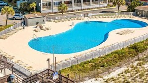 Ett hotell med en stor pool, flera balkonger och ett område vid stranden.