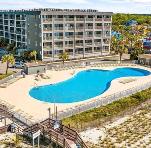 Um hotel com uma piscina grande, várias varandas e uma área de praia.
