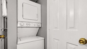 A white washing machine and dryer in a room with a closed door and a doorbell. - Seawatch Condo | Marsh View & Pool  | Cozy 2BR  |  Relaxing Amenities Free Travel Insurance on weekly rentals (Murrells Inlet)