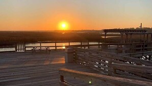 A wooden pier extending into a body of water during sunset.