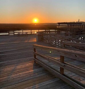 A wooden pier extending into a body of water during sunset.