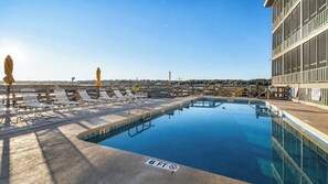 A swimming pool with lounge chairs and umbrellas, a lifeguard tower, and a view of the cityscape. - Seawatch Condo | Marsh View & Pool  | Cozy 2BR  |  Relaxing Amenities Free Travel Insurance on weekly rentals (Murrells Inlet)