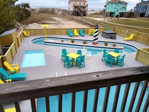 A wooden deck with a pool, outdoor seating, and a lighthouse model.