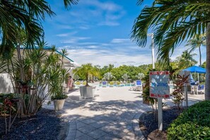 A pool area with lounge chairs and a sign indicating pool rules.