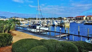 A marina with boats docked, a wooden walkway, and buildings in the background. - Spacious 6BR Oceanview Condo w/ Pool & Hot Tub (North Myrtle Beach)