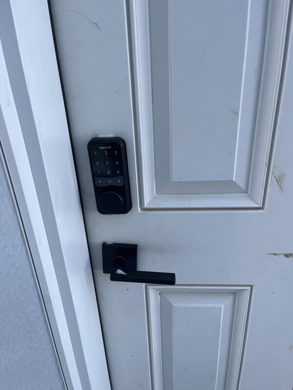 A white door with a black doorbell and a door handle.