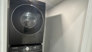 Une buanderie équipée de deux machines à laver et de deux sèche-linge à chargement frontal, placés l’un sur l’autre.