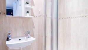 Une salle de bain avec un lavabo blanc, un miroir et une cabine de douche en verre.