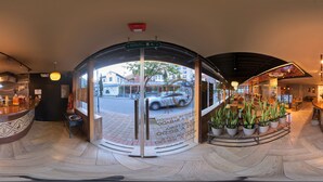 Een hotel lobby met een gebogen receptiebalie, een glazen deur en een bloembekarrangement.